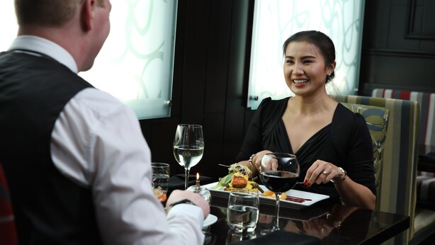 Une table à manger avec une assiette de nourriture, des verres à vin et une bougie.