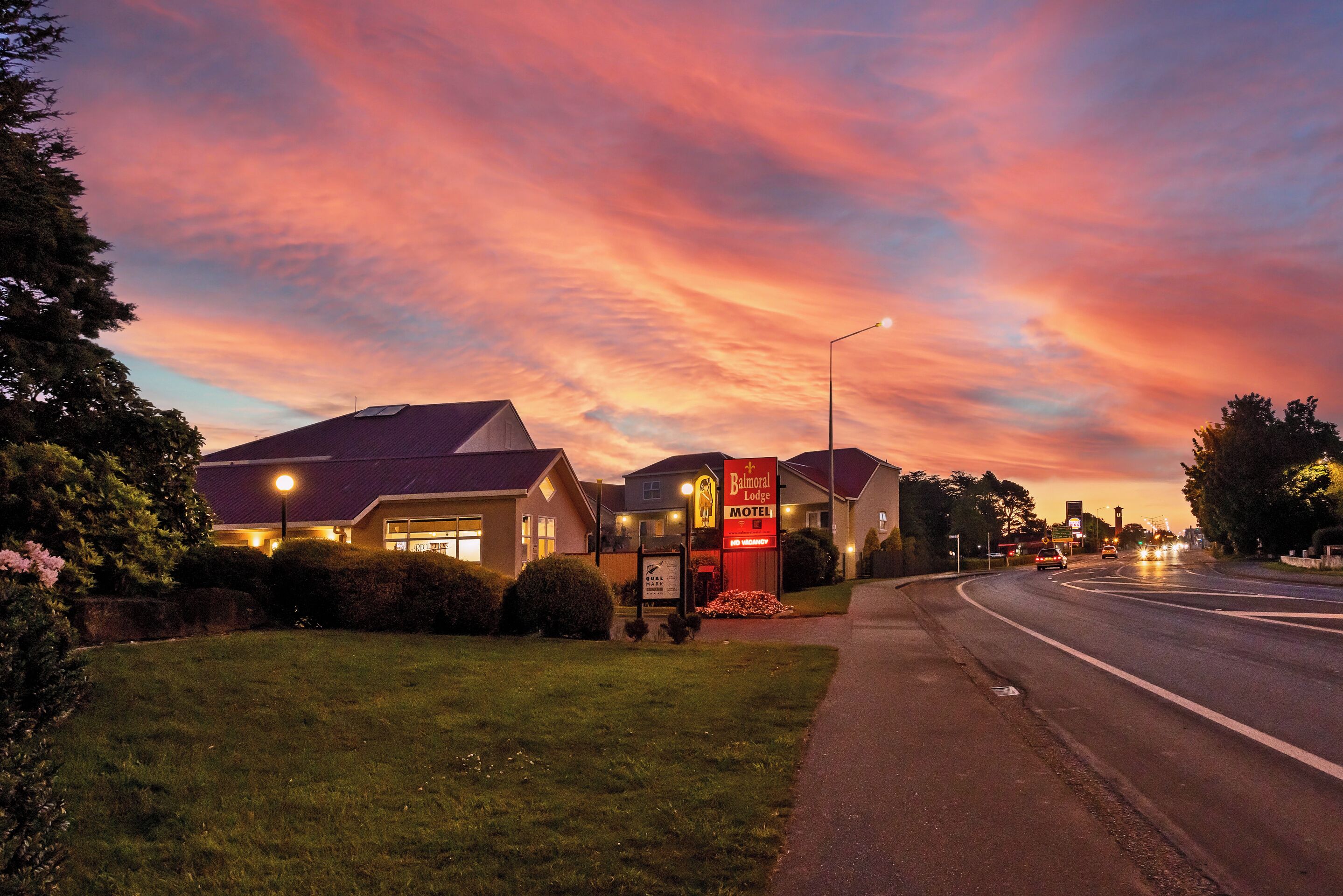 A motel with a signboard, a well-maintained lawn, and a road curving to the right.