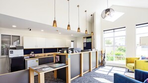 A modern office space with cubicles, a reception desk, and a yellow sofa. - Balmoral Lodge Motel (Invercargill)