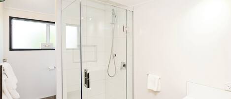 A modern bathroom with a glass-enclosed shower, a white bathtub, and a visible towel rack.