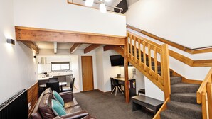 A cozy interior with a wooden staircase, a leather sofa, and a dining area. - Balmoral Lodge Motel (Invercargill)