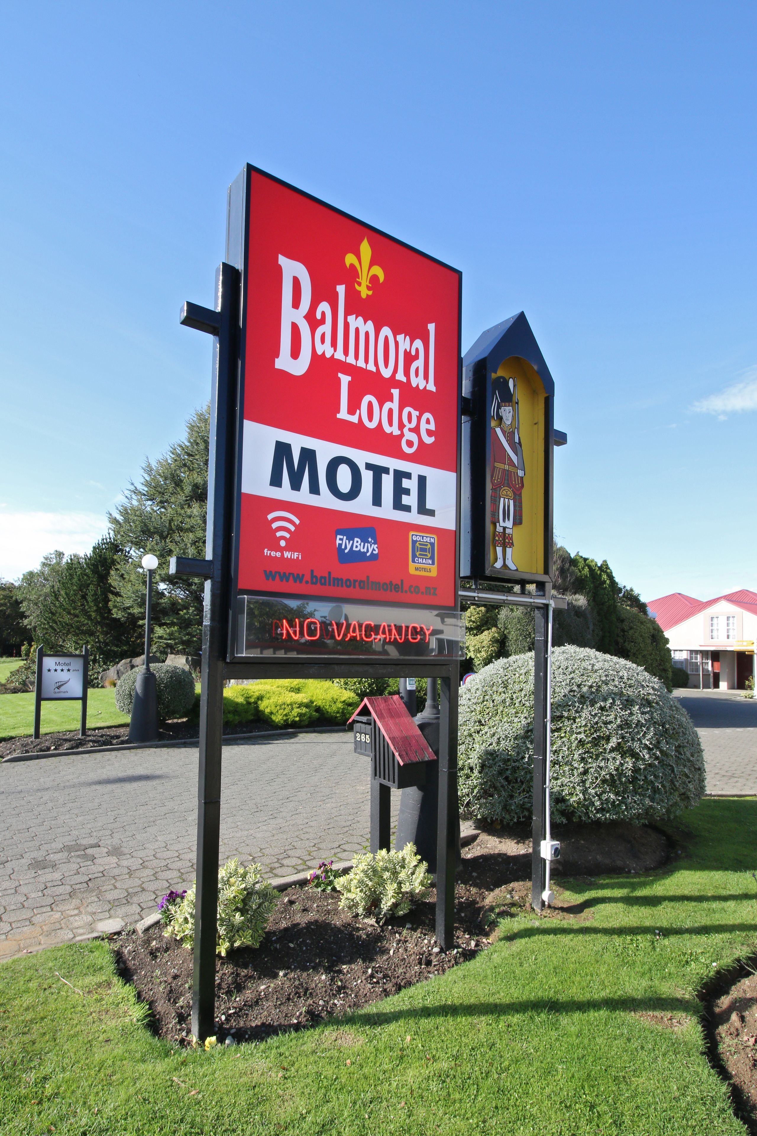 A motel sign with a red background and white lettering, indicating the name 'Balmoral Lodge'.
