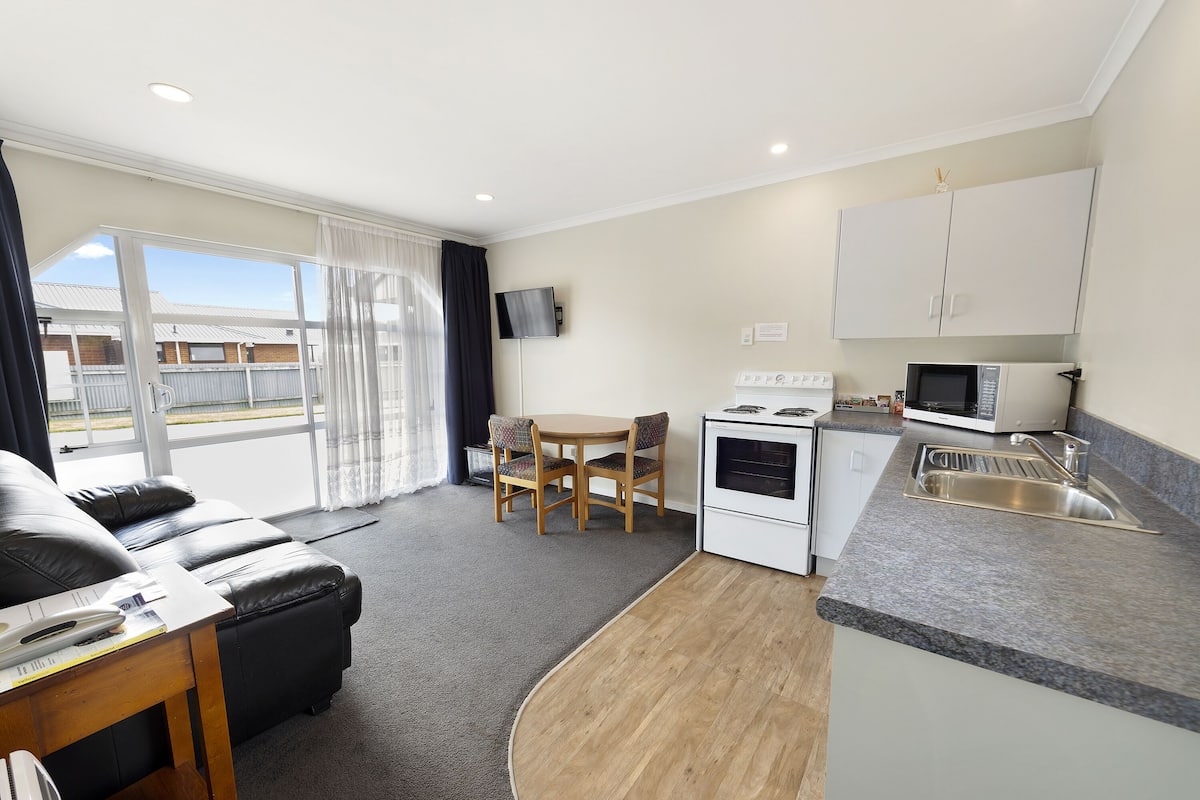 A compact living space with a kitchenette, a dining area, and a sofa.