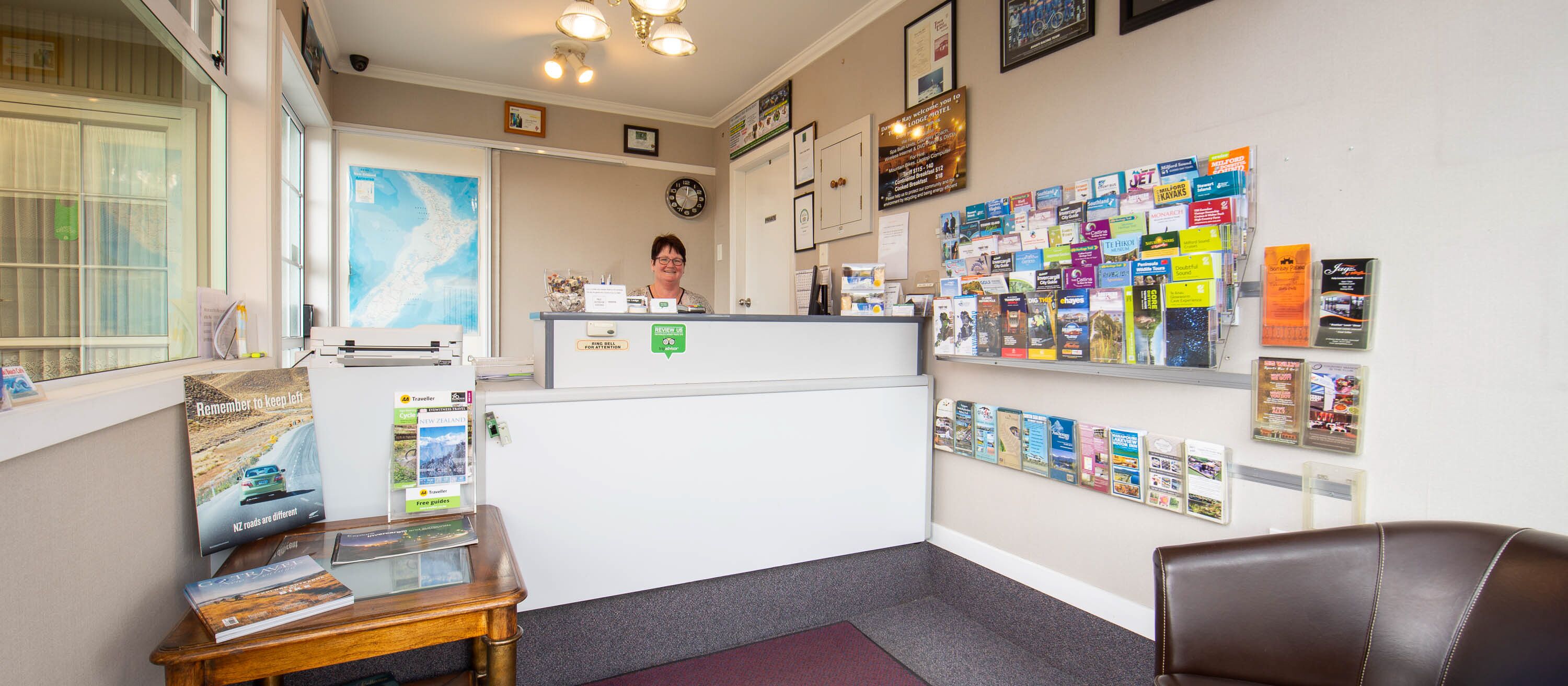 A reception area with a desk, a clock, and a wall displaying various travel brochures.
