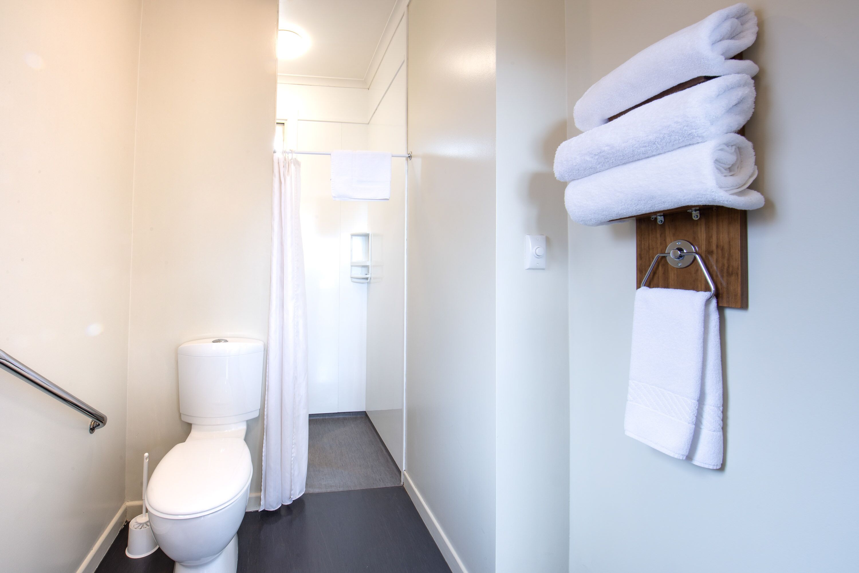 Une salle de bain équipée de toilettes, d’un rideau de douche et d’un porte-serviettes avec des serviettes.