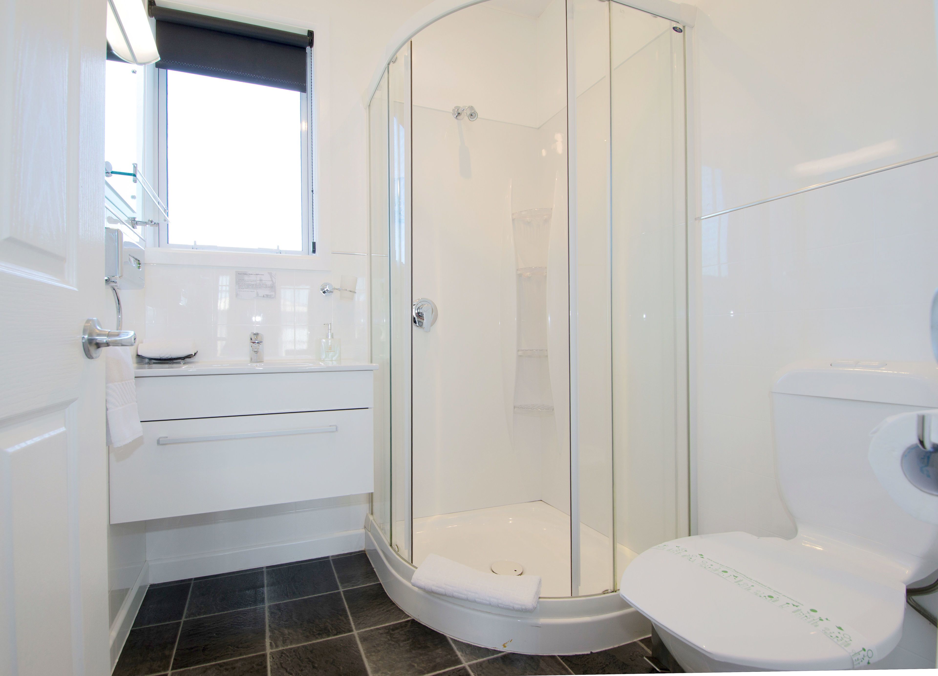 A modern bathroom with a glass-enclosed shower, a toilet, and a sink.