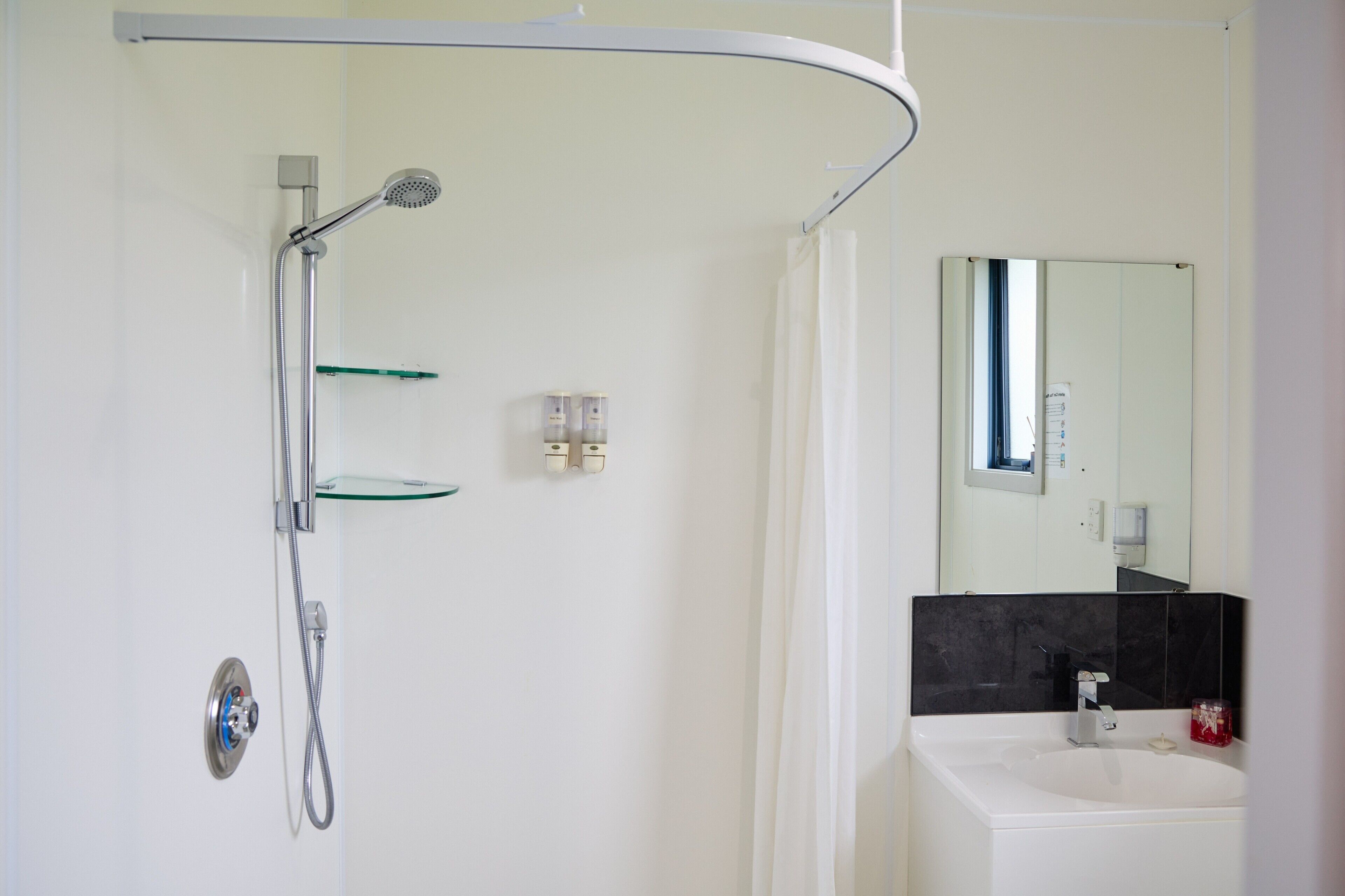 Ein modernes Badezimmer mit Dusche, Waschbecken und Spiegel.