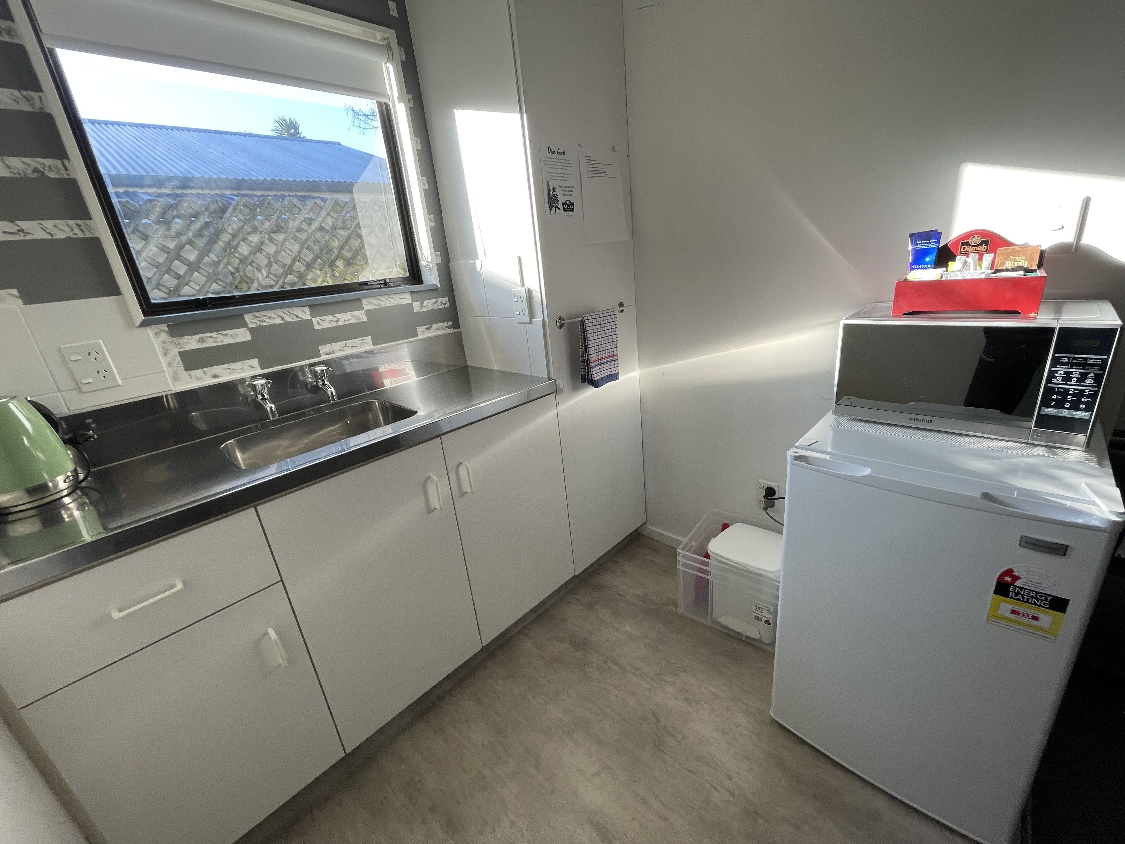 A modern kitchen with a stainless steel countertop, a built-in sink, and a microwave.