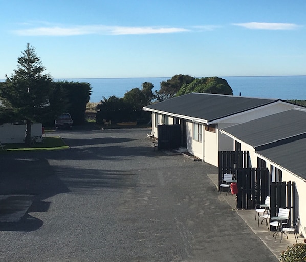 Un parque de caravanas con una amplia zona de estacionamiento, un edificio de techo plano y vistas al mar.