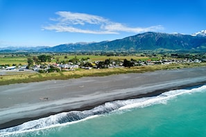 Un pueblo costero con playa, casas y montañas al fondo.