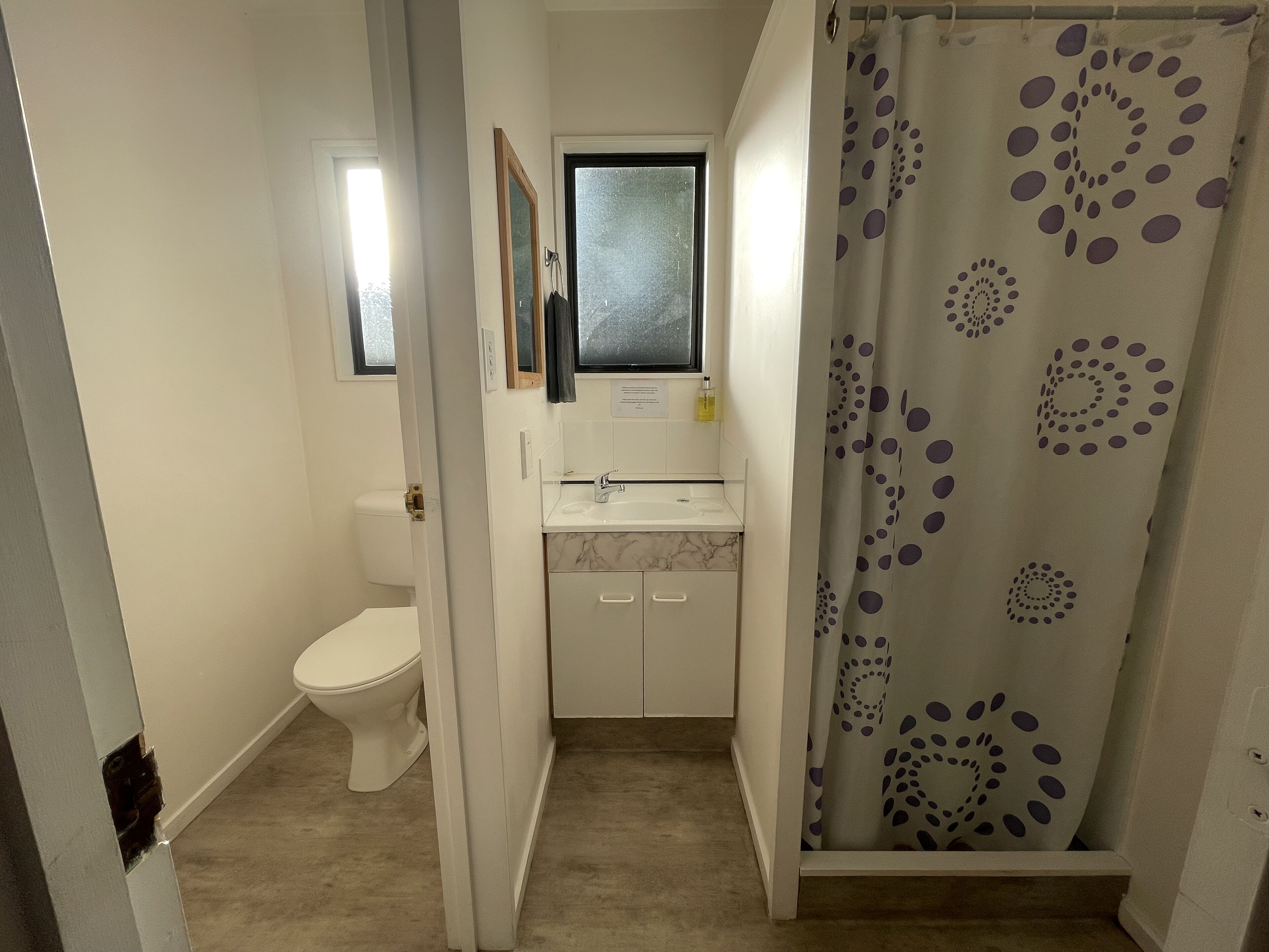 A small bathroom with a toilet, a sink, and a shower curtain with a circular pattern.
