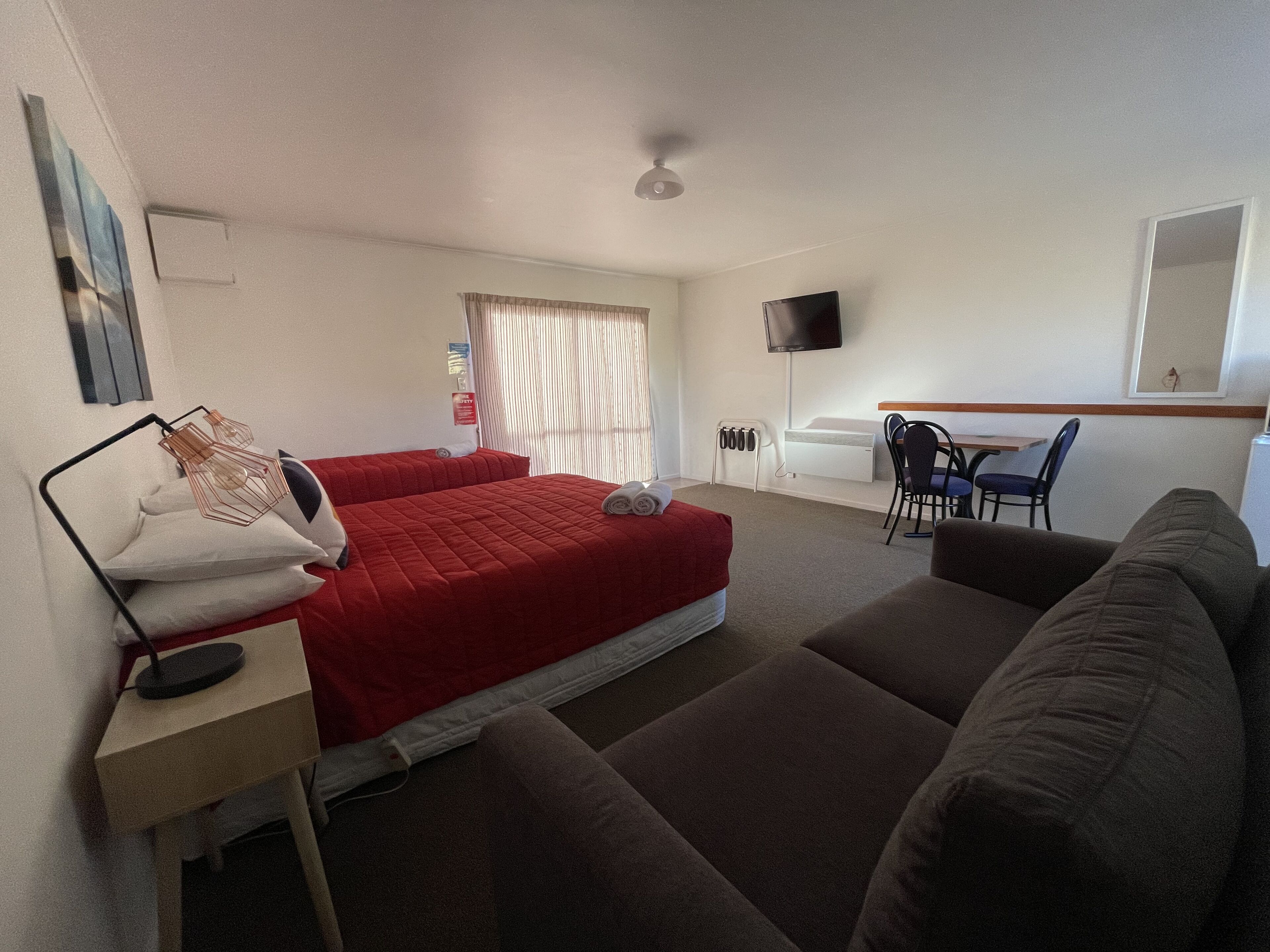 Una habitación de hotel con cama, escritorio, silla y sofá.