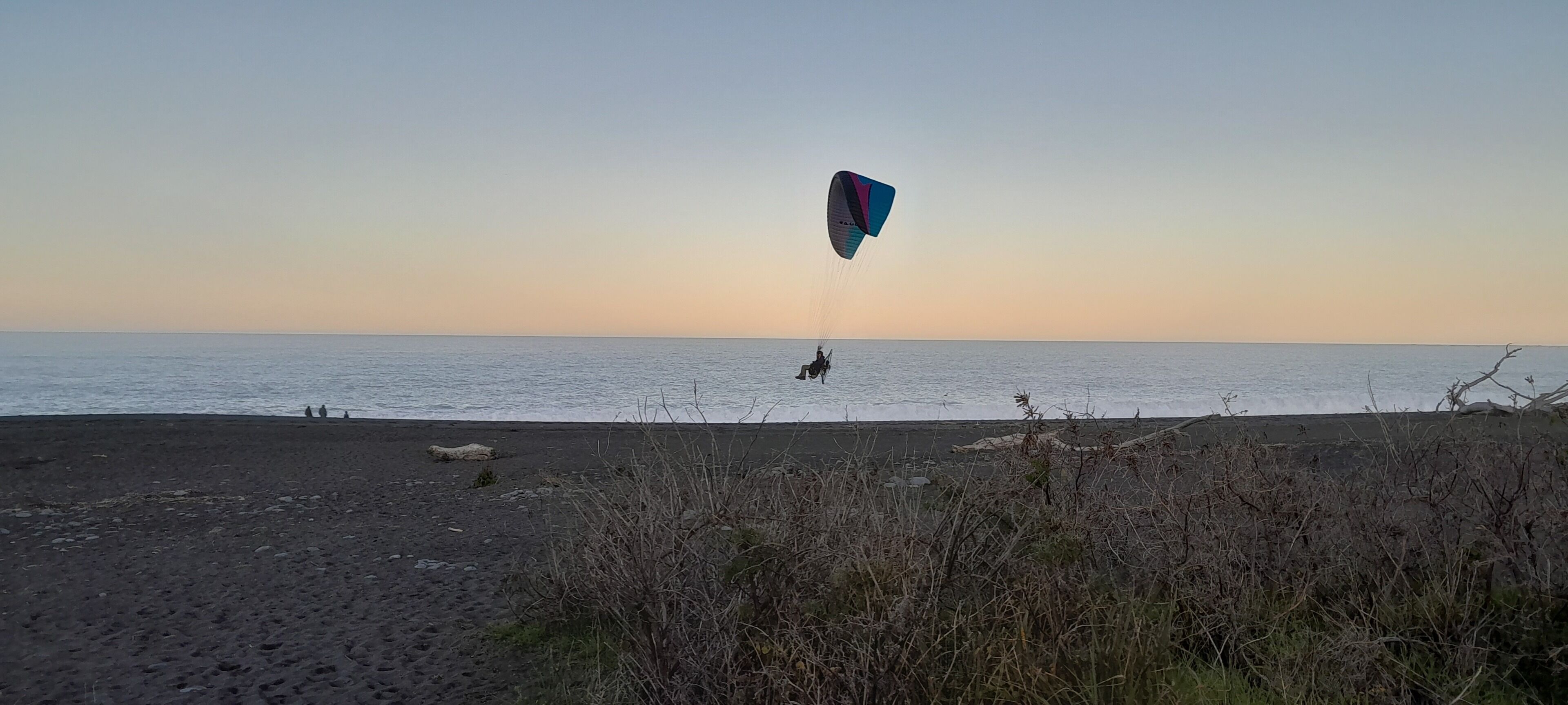 A beach with a person kite surfing.