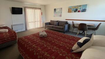 A hotel room with a large bed, a sofa, a desk, and a chair.