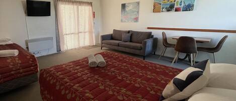A hotel room with a large bed, a sofa, a desk, and a chair.
