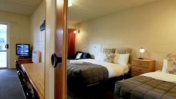 Une chambre d’hôtel avec un lit, une table de chevet, une lampe et un téléviseur posé sur un meuble.