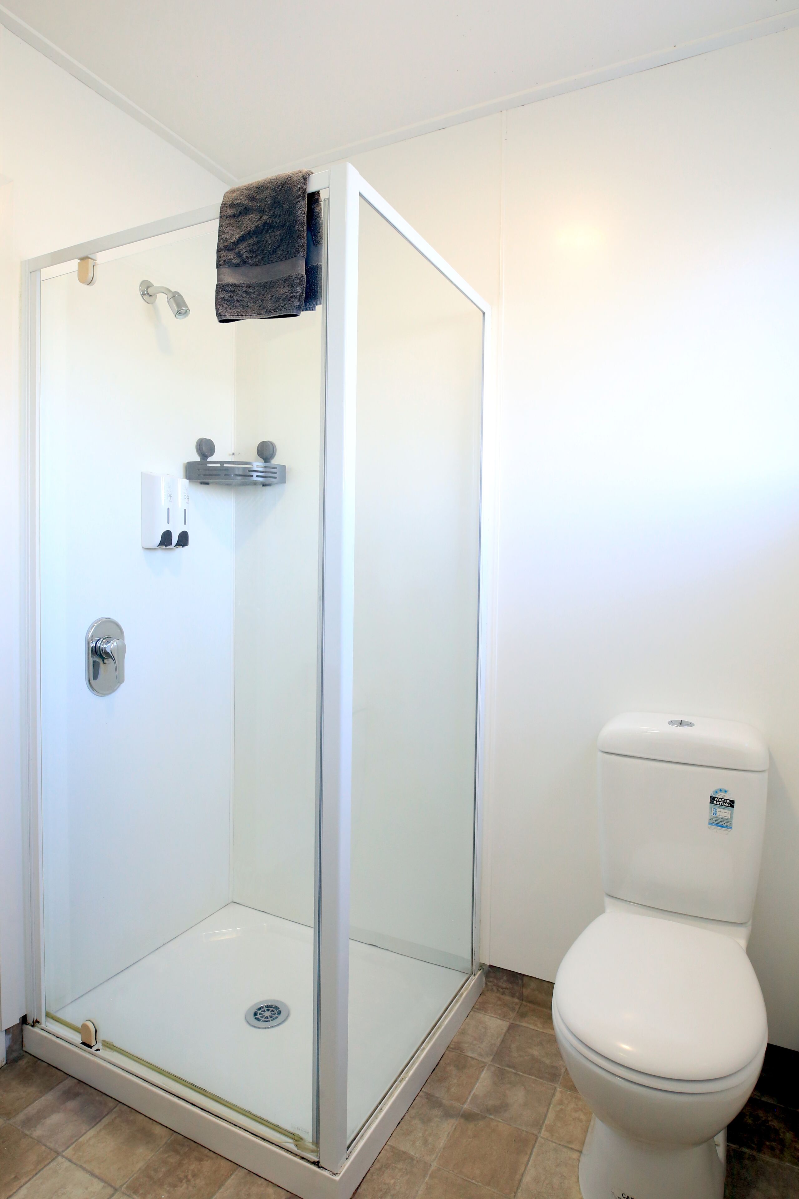 Baño con ducha de vidrio, inodoro y barra para toallas.