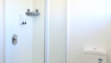 Baño con ducha de vidrio, inodoro y barra para toallas.