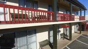 A two-story building with a red balcony railing, outdoor seating, and a sign advertising secure wireless internet.