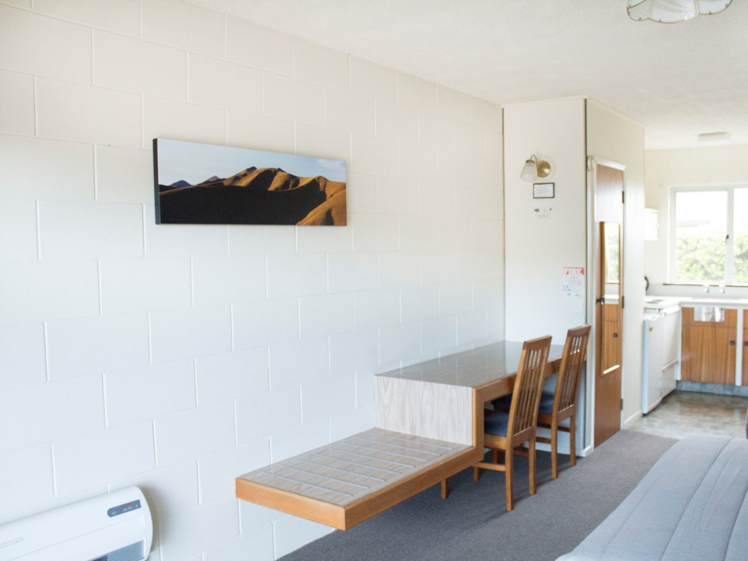 Una habitación con una mesa de comedor, sillas, un banco, un cuadro en la pared y una ventana.