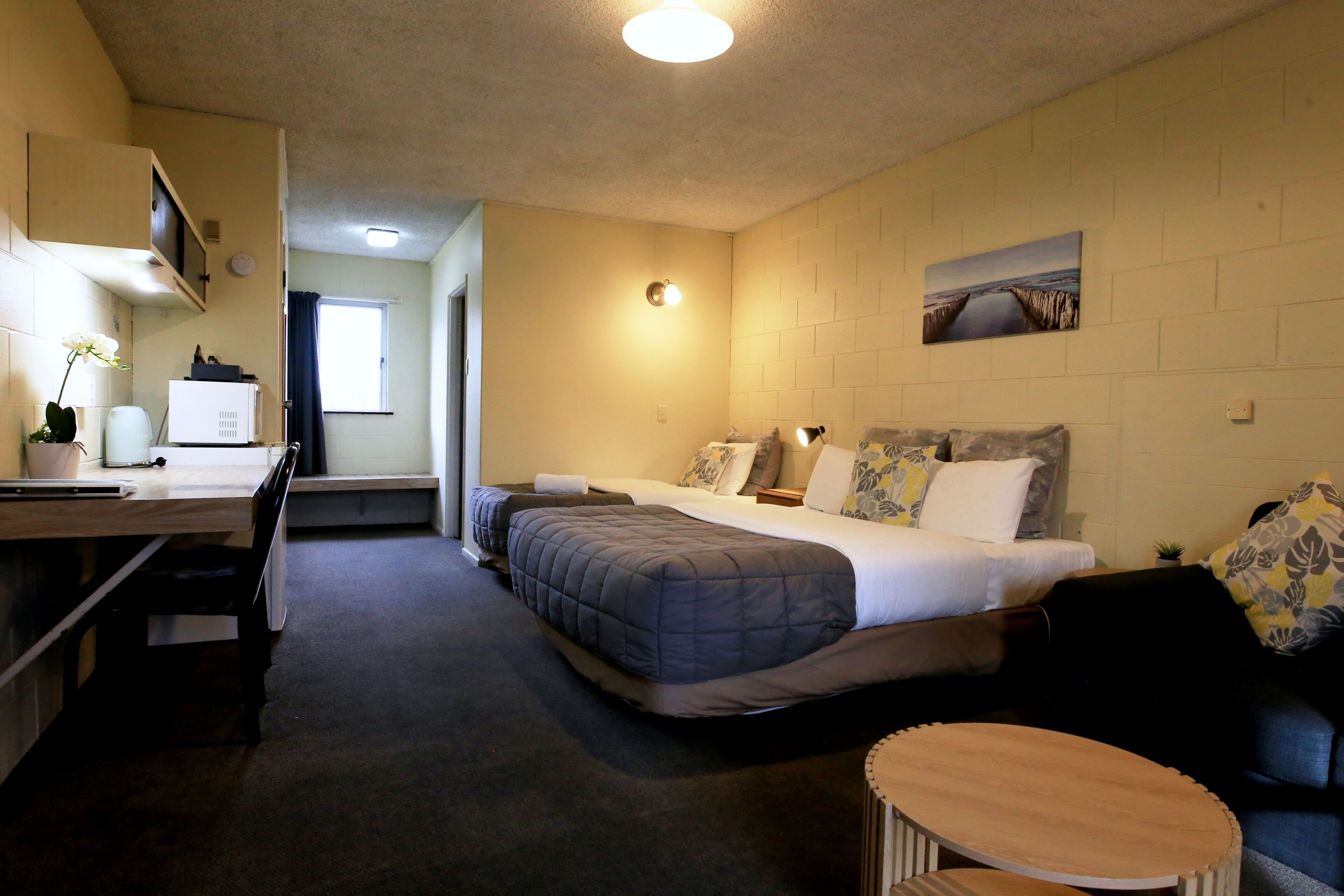 Een hotelkamer met een bed, een bureau, een stoel, een klein tafeltje en een bank.