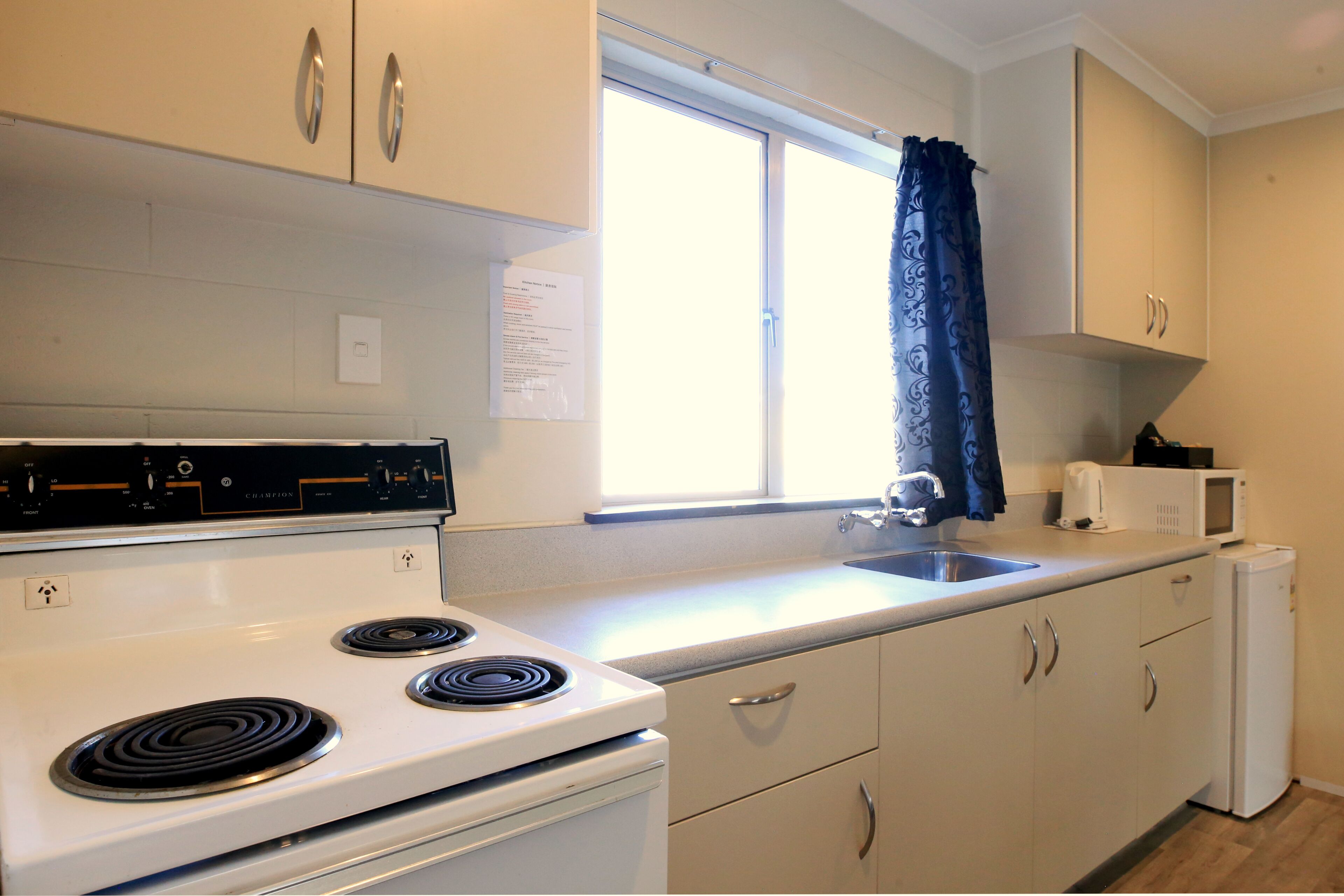 A compact kitchen with a white stove, a sink, and a refrigerator.