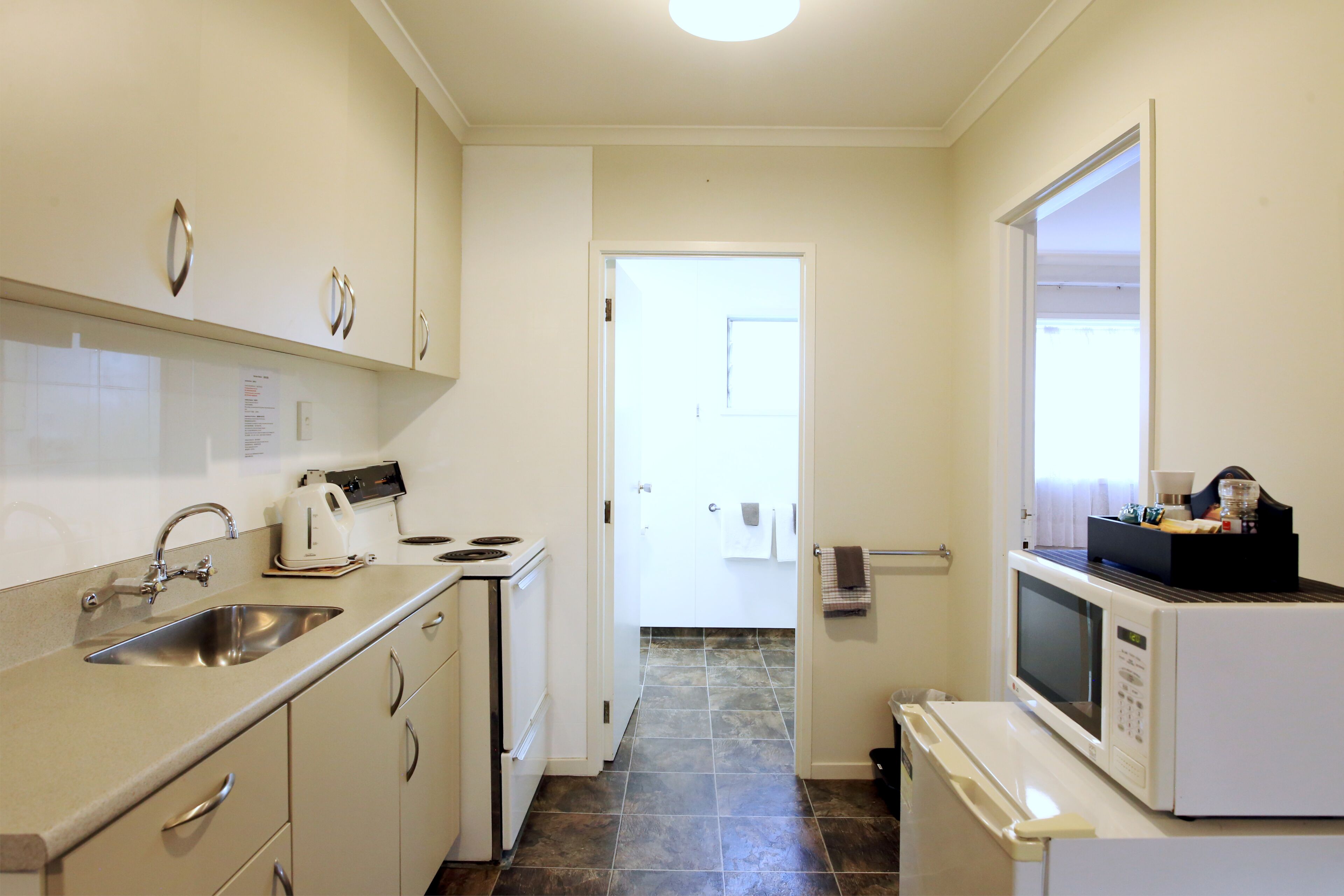 A compact kitchen with a sink, stove, microwave, and a small refrigerator.