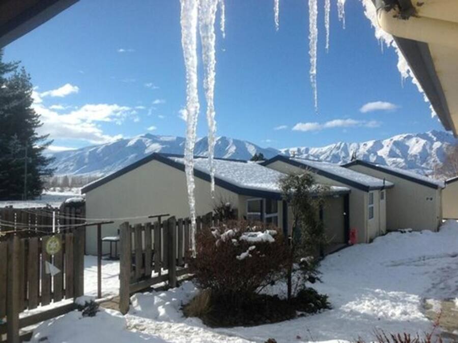 A house with a snow-covered roof and mountains in the background.
