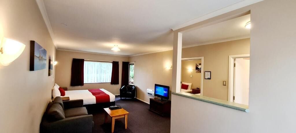 A hotel room with a bed, a sofa, a TV, and a small table.