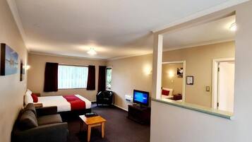 A hotel room with a bed, a sofa, a TV, and a small table.