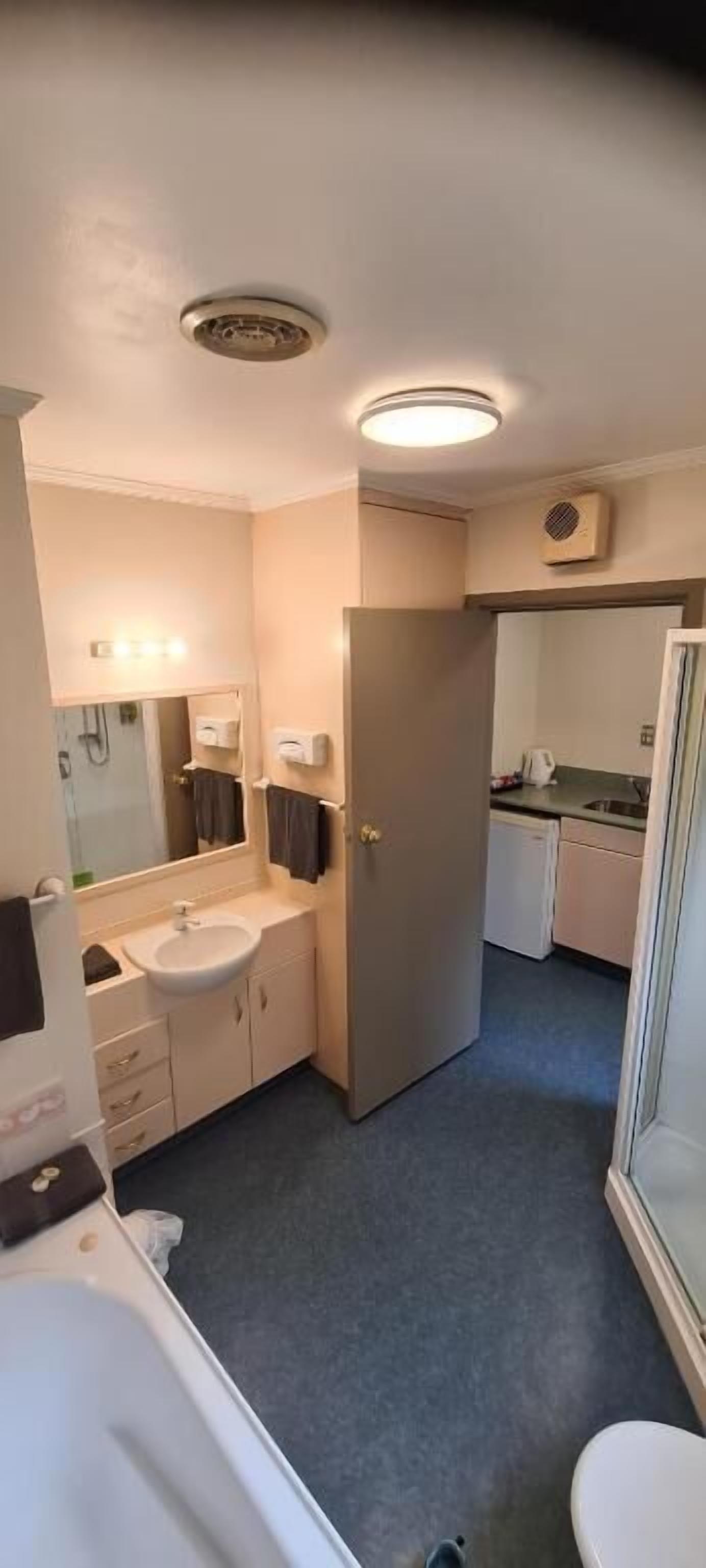 Ein kleines Hotelzimmer mit Bad, einer Küchenzeile und einer Dusche.