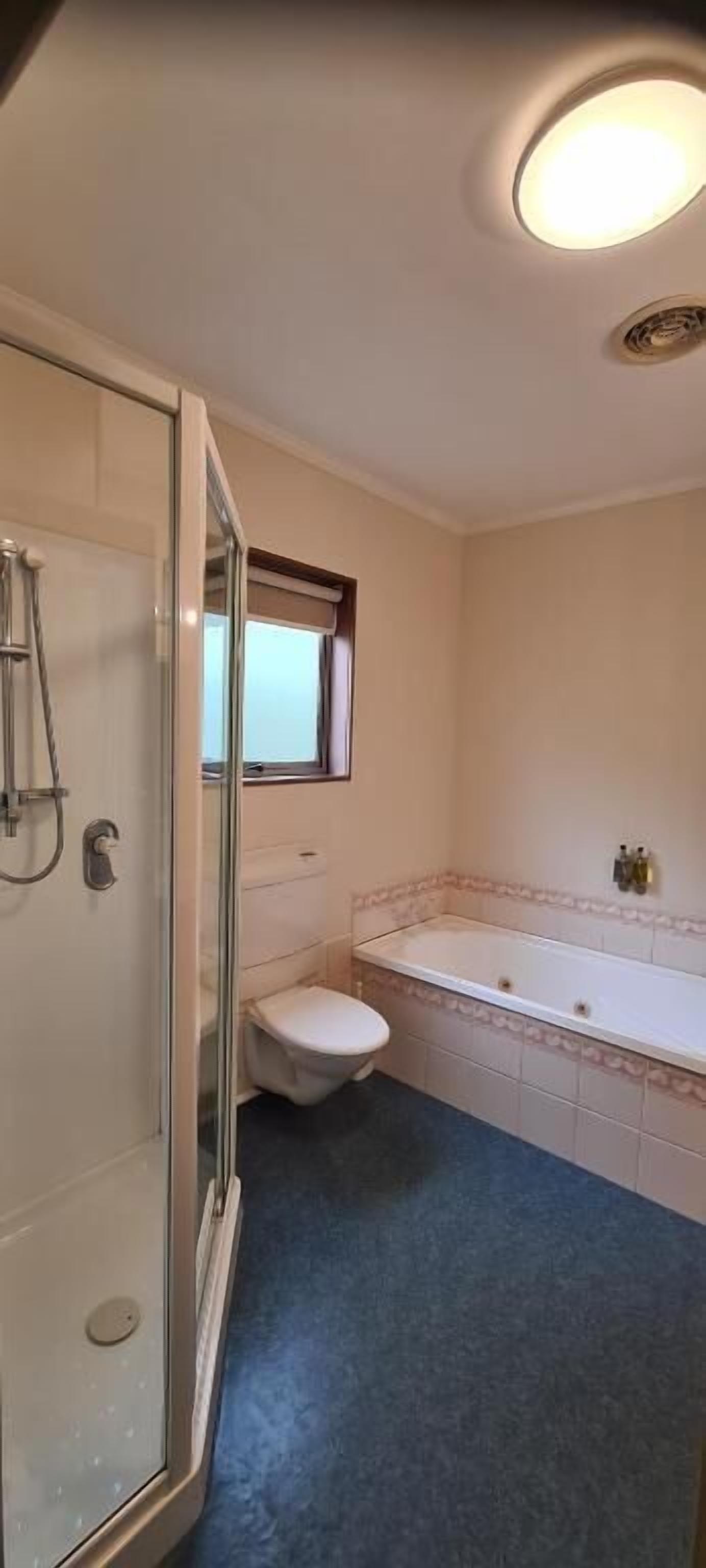 Een badkamer met een glazen douchecabine, toilet en bad.