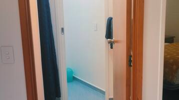 Un pasillo estrecho con una puerta de madera a la derecha, una alfombra azul y una pared blanca.