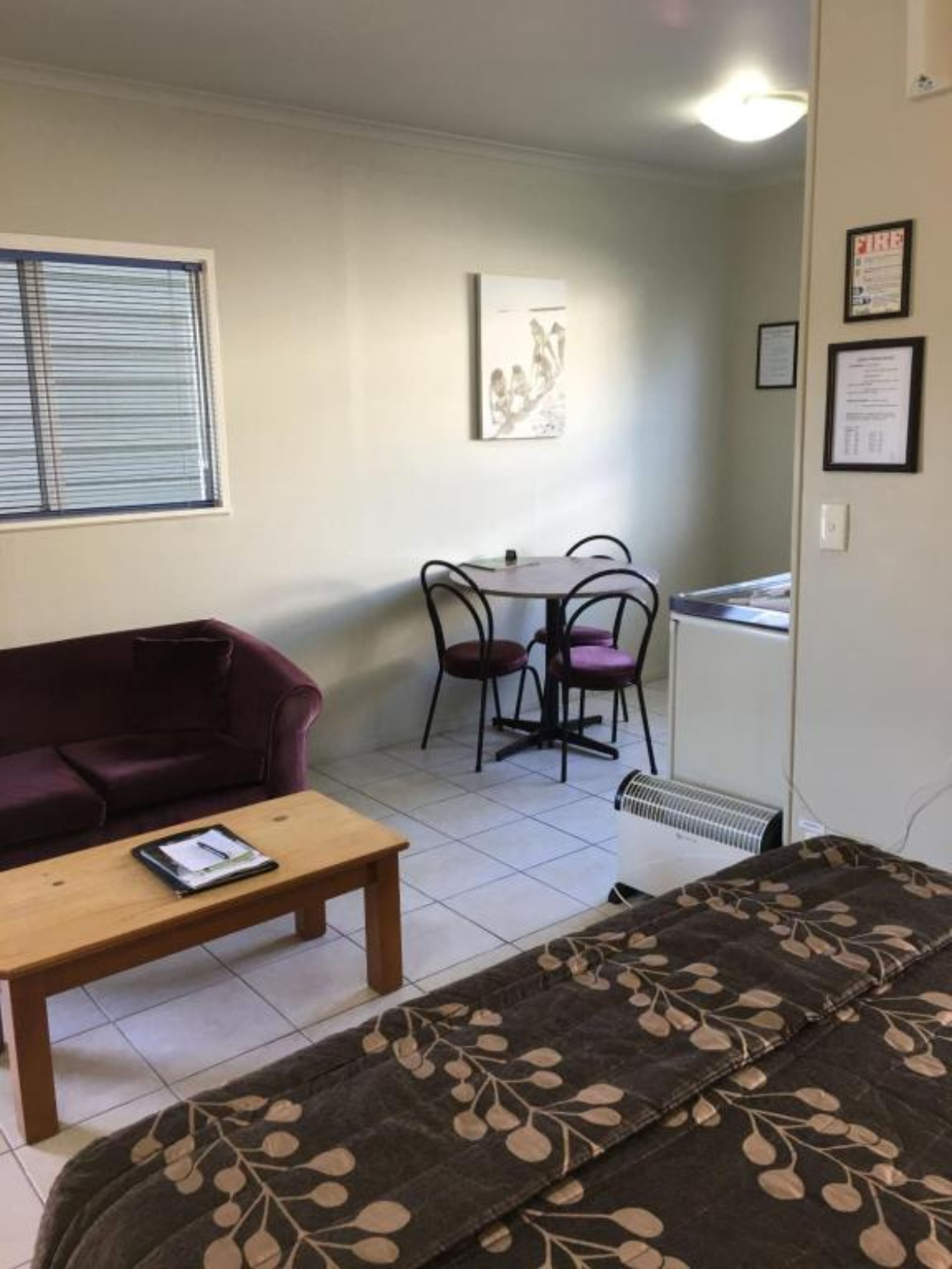 A compact living space with a sofa, a small table, a dining area with chairs, and a radiator.