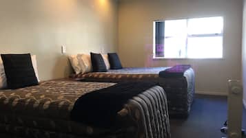 A hotel room with two beds, a window, and a standing heater.
