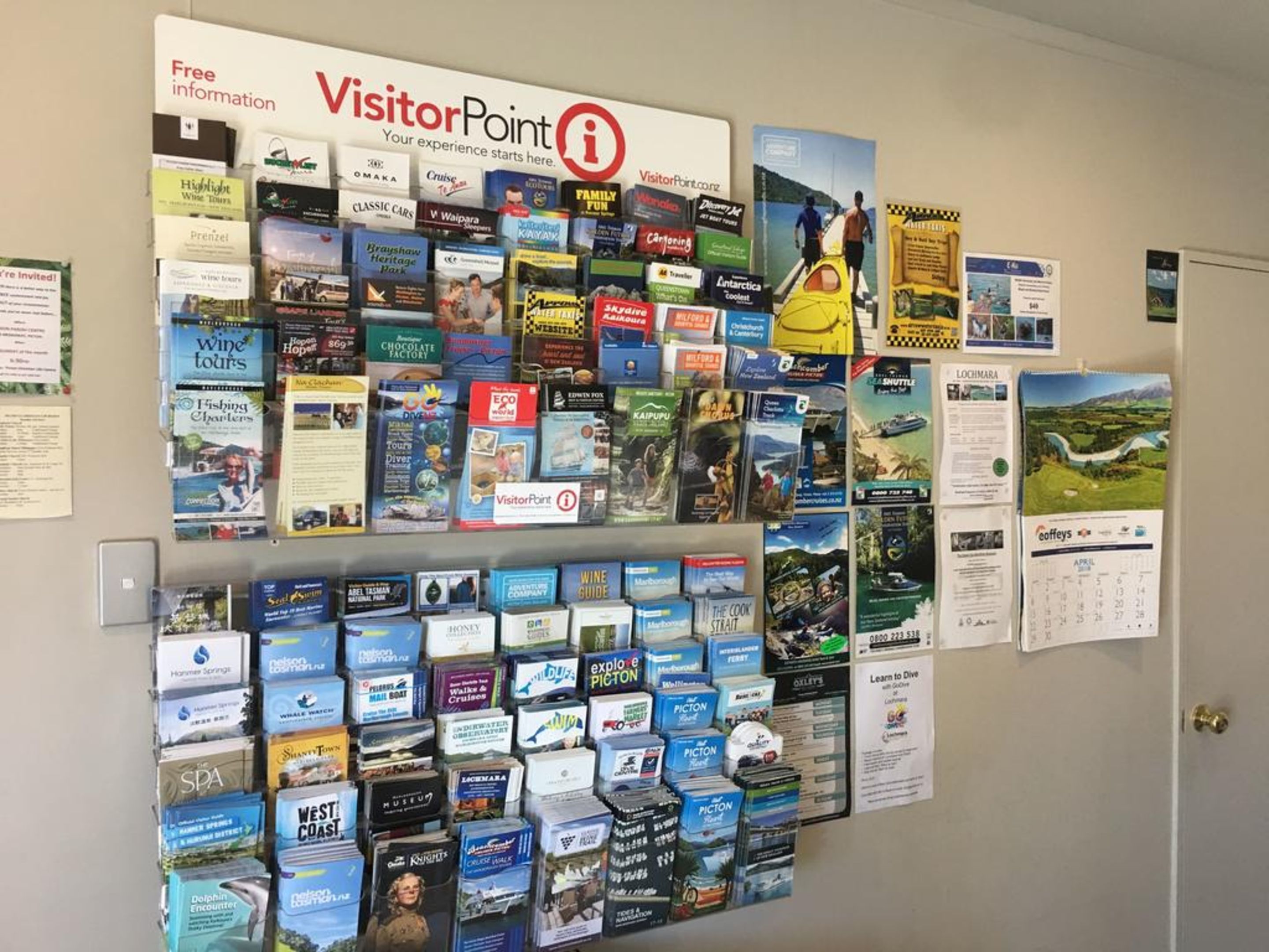 Pared decorada con diversos folletos turísticos y mapas, incluyendo temas como catas de vino, actividades familiares y atracciones locales.