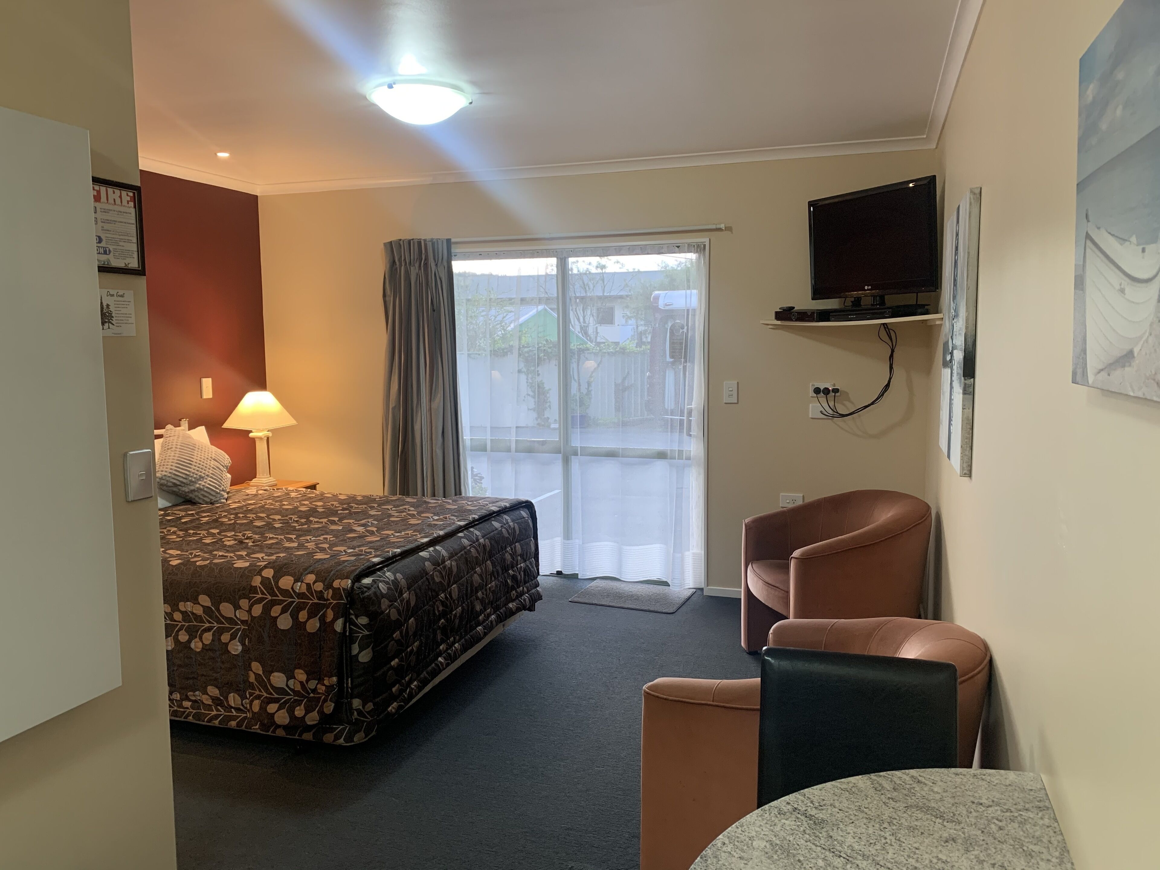 A hotel room with a bed, a desk, a chair, a television, and a window with curtains.