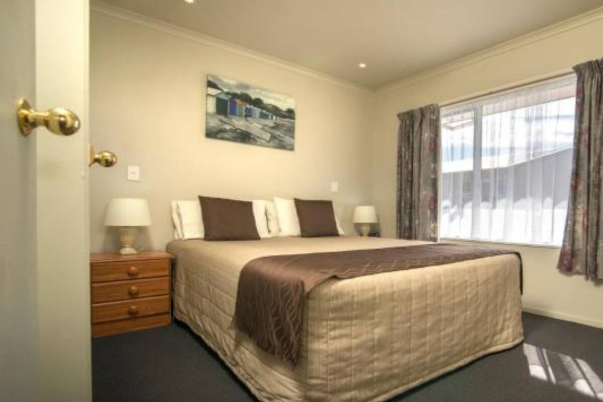 A hotel room with a bed, bedside tables, a painting on the wall, and a window with curtains.