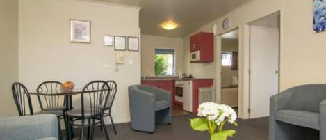Un espace de vie compact comprenant un coin repas, une kitchenette et un coin salon avec une petite table et des chaises.