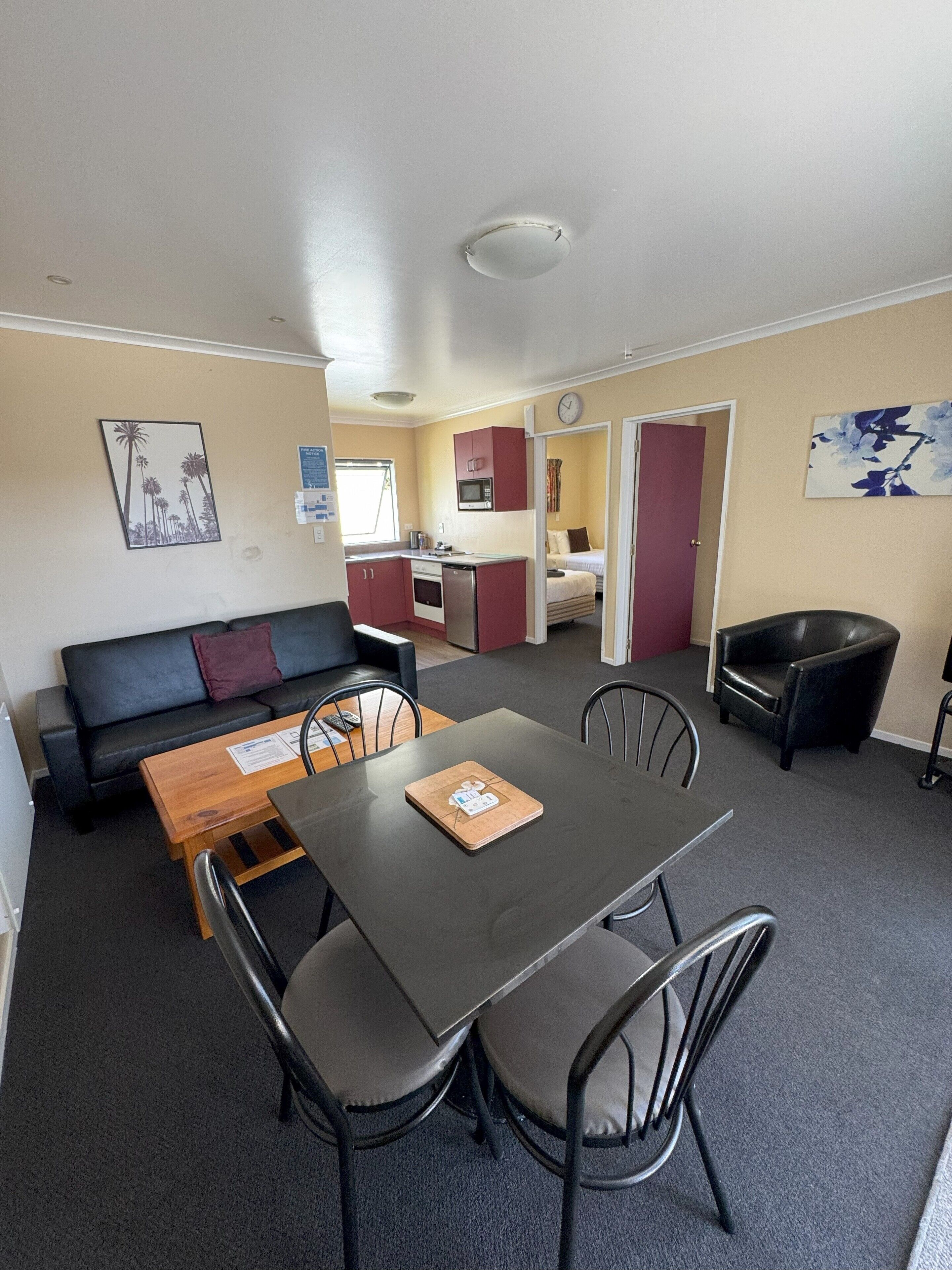 Een functionele ruimte met een eettafel, stoelen, een bank, een kitchenette en een afzonderlijke slaapruimte.