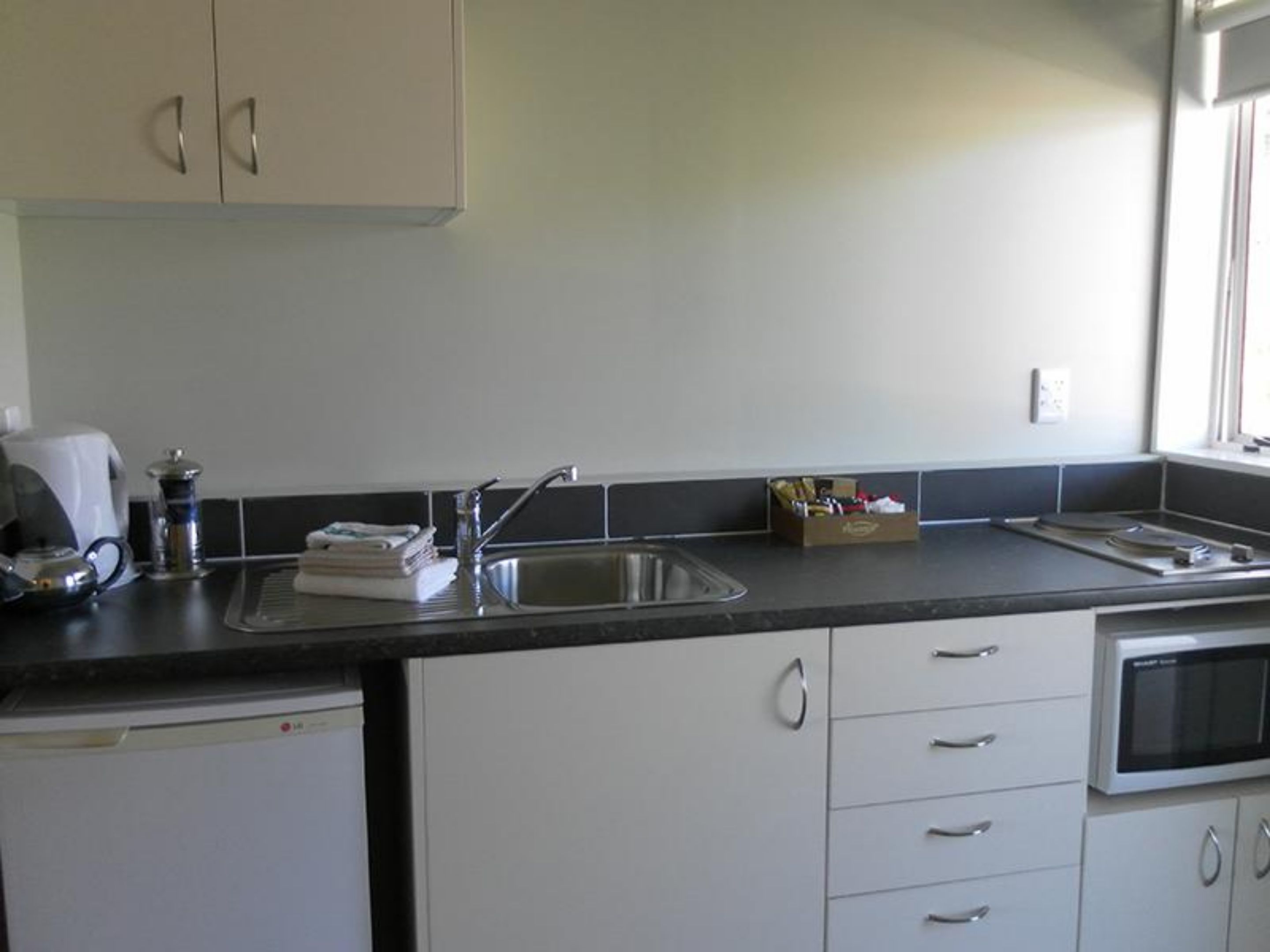 A compact kitchen with a sink, a coffee maker, and a microwave.