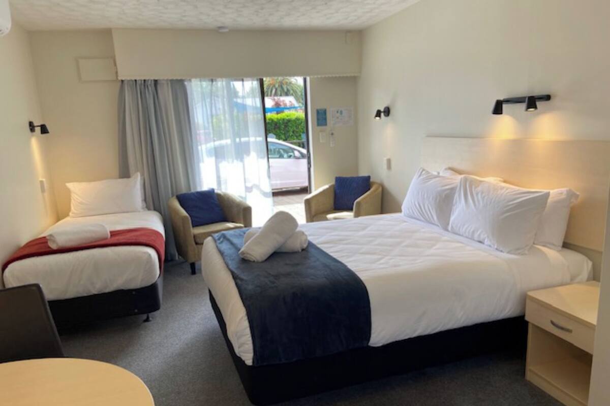 Una habitación de hotel con dos camas individuales, una cama grande, un escritorio y una silla.