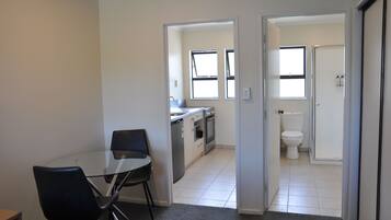 A modern apartment with a dining area, kitchen, and bathroom.