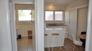 A modern kitchen with a bar area, a dining table, and a white chair. - Balmoral Motel (Nelson)