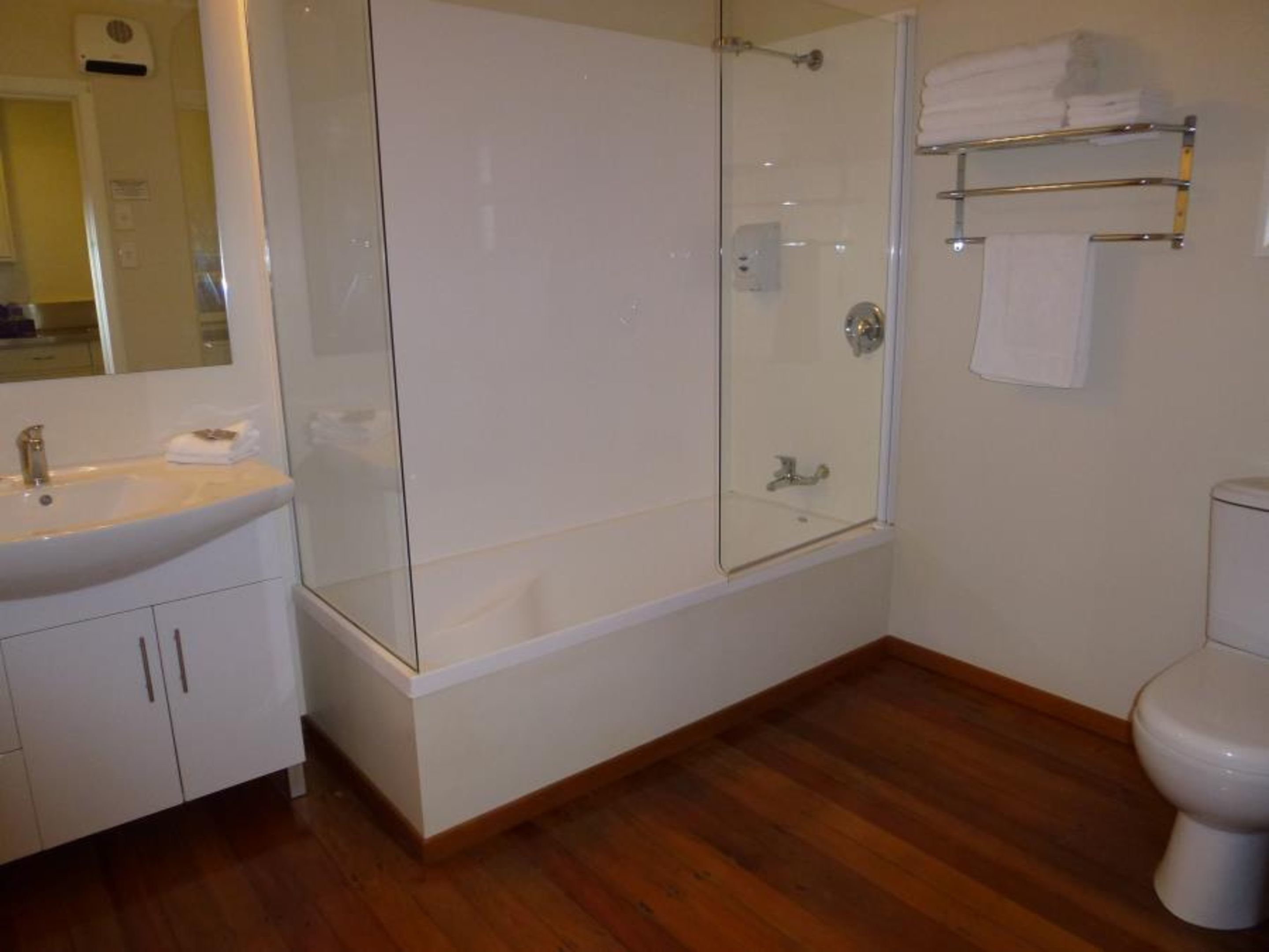 A modern bathroom with a glass-enclosed shower, a white sink, and a toilet.