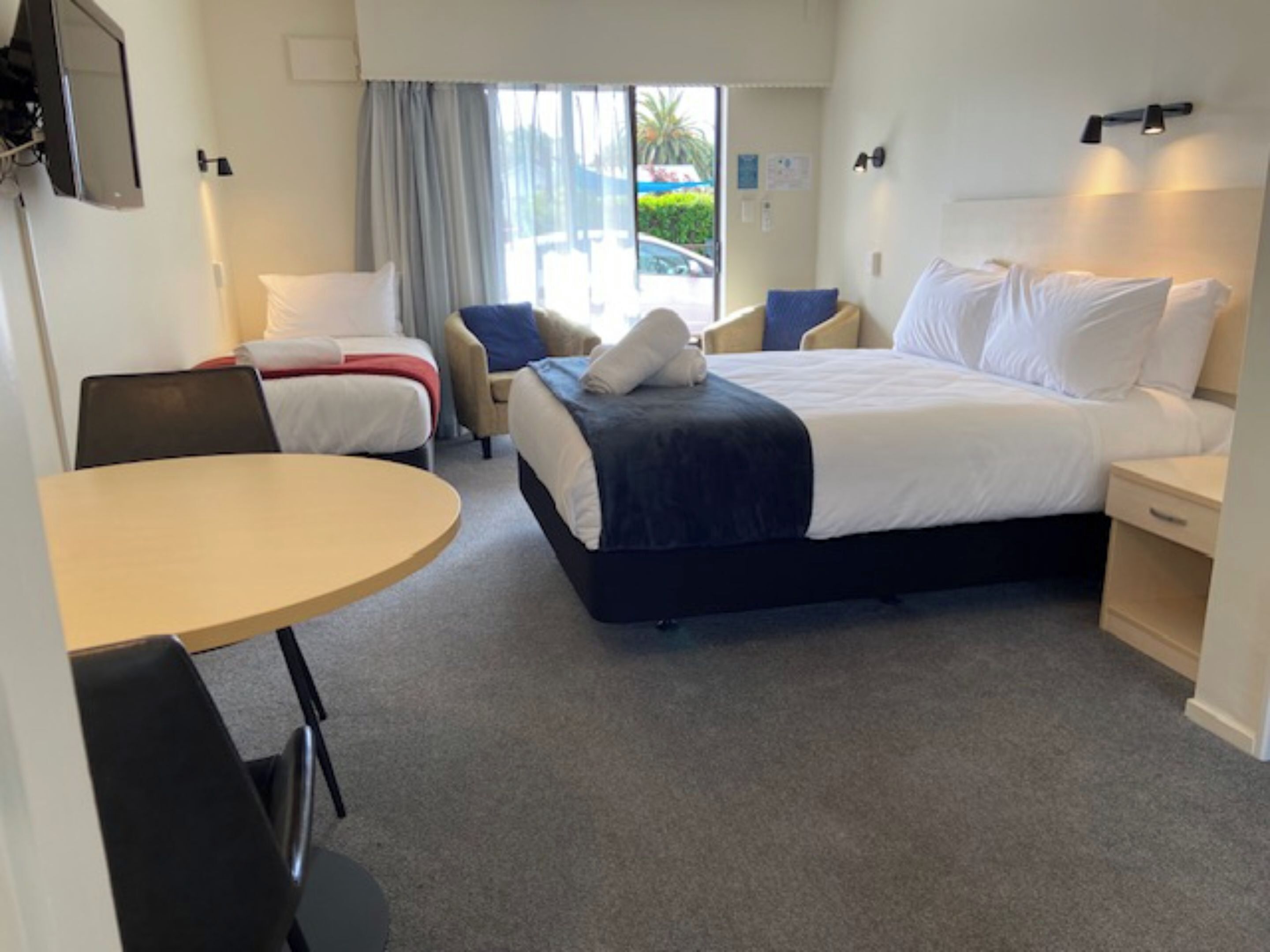Ett hotellrum med en säng, ett skrivbord, en stol och utsikt över omgivningarna.