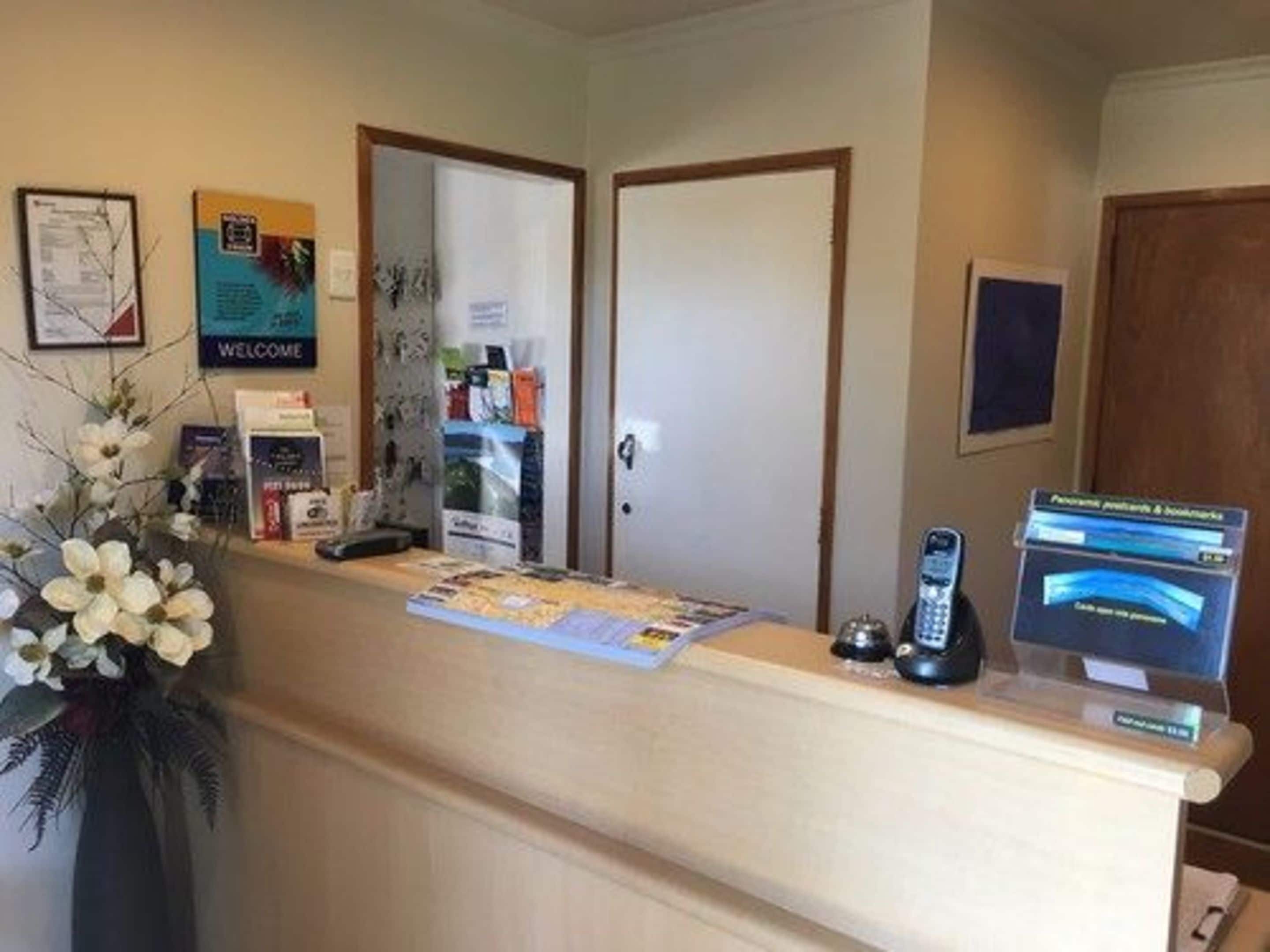 A reception area with a counter, a welcome sign, a map, and a phone.