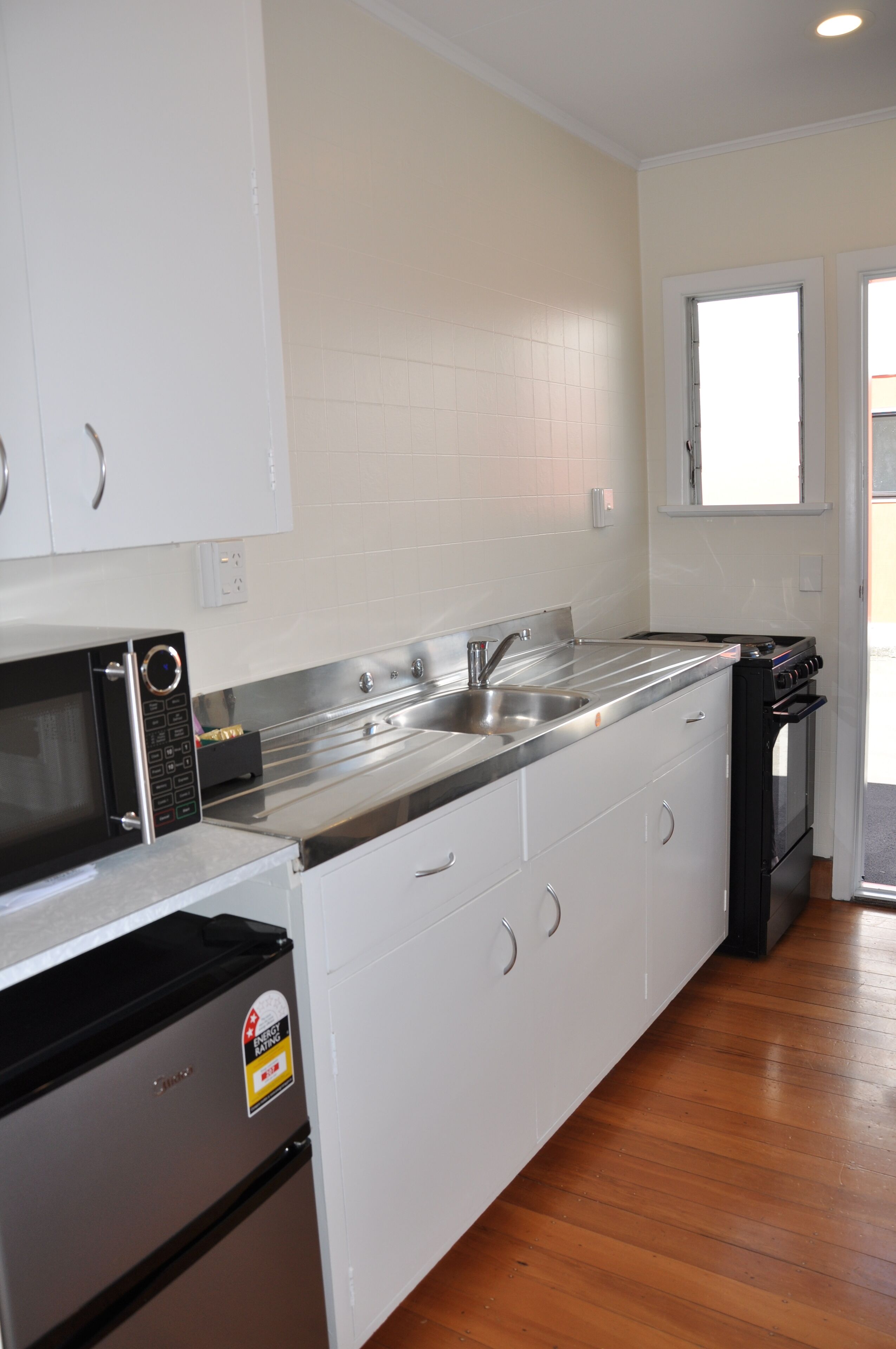 A kitchen with white cabinets, stainless steel appliances, and a wooden floor.