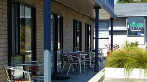A motel reception area with outdoor seating and a brick facade. - Balmoral Motel (Nelson)