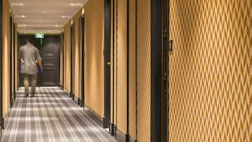 Un pasillo de hotel con paredes y puertas estampadas, una recepción al final y suelo alfombrado.